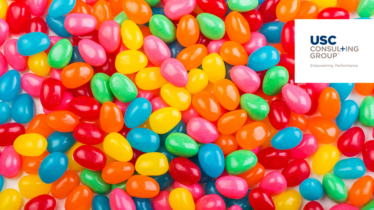 Haufen bunter Jelly Beans mit dem Logo der USC Consulting Group in der Ecke.