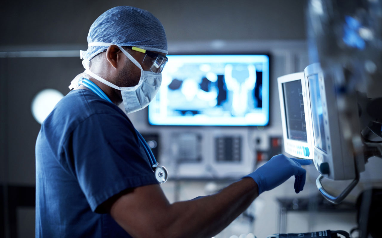 Doctor in surgical scrubs reading a monitor.