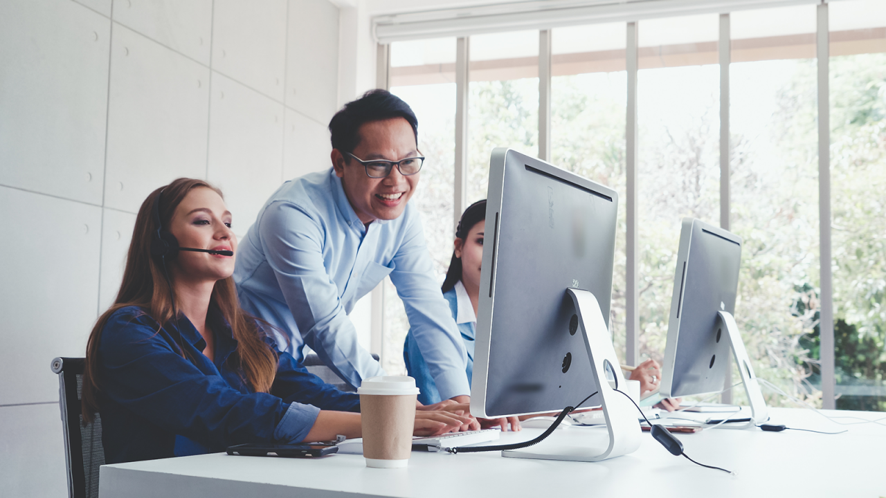 3 people working together at a workstation in an office